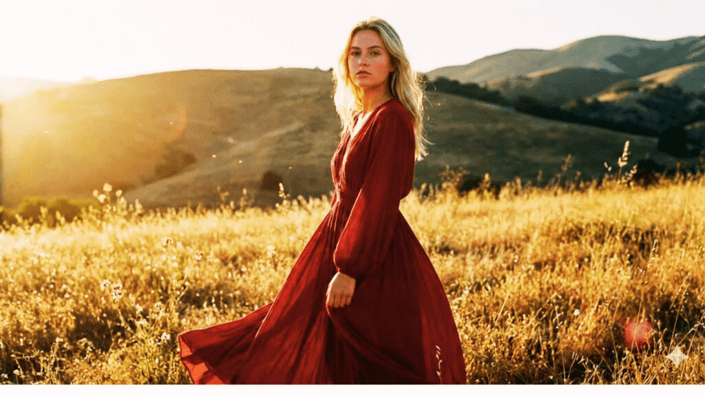 chosen life Blonde woman in a red dress embracing her chosen life with confidence and authenticity, standing in a sunlit field.