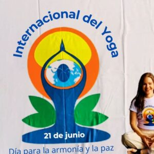 Arlene De Angelis sentada frente a afiche D'ia Internacional del Yoga